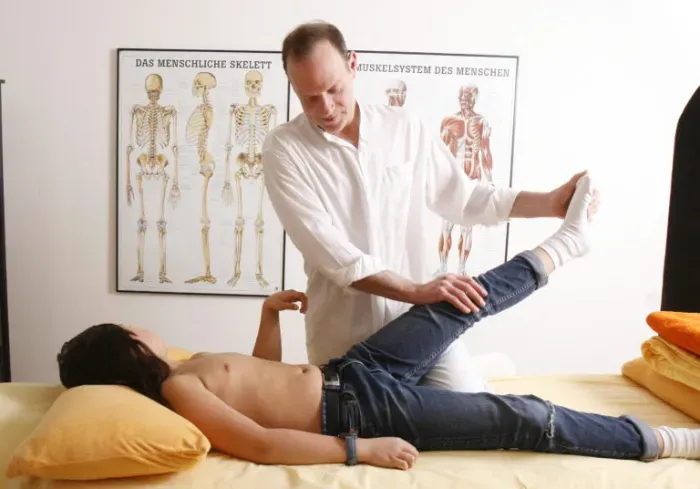 Heilpraktiker bei der Behandlung am Bein des Patienten